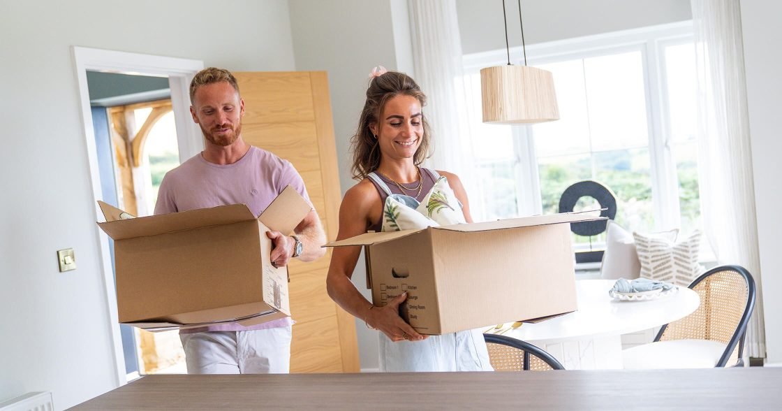 Devonshire Homes Devonshire Move Scheme Couple Carrying Boxes Into Kitchen